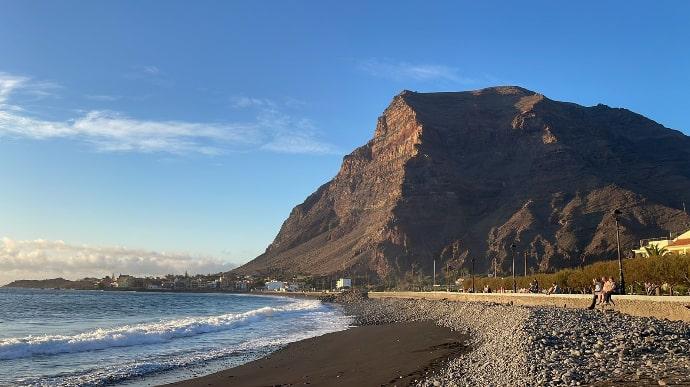Valle Gran Rey Playa de Valle Gran Rey, donde se ve la montaña, personas paseando y la avenida del paseo marítimo